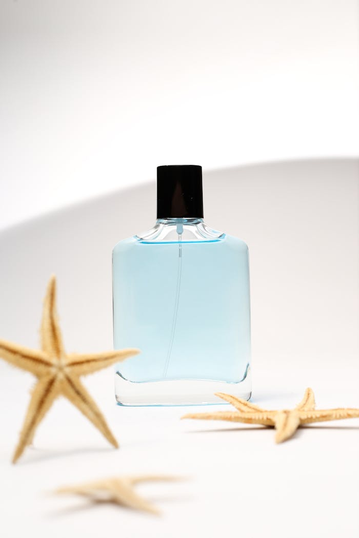 A minimalist shot of a blue perfume bottle surrounded by starfish, evoking a sense of freshness and relaxation.